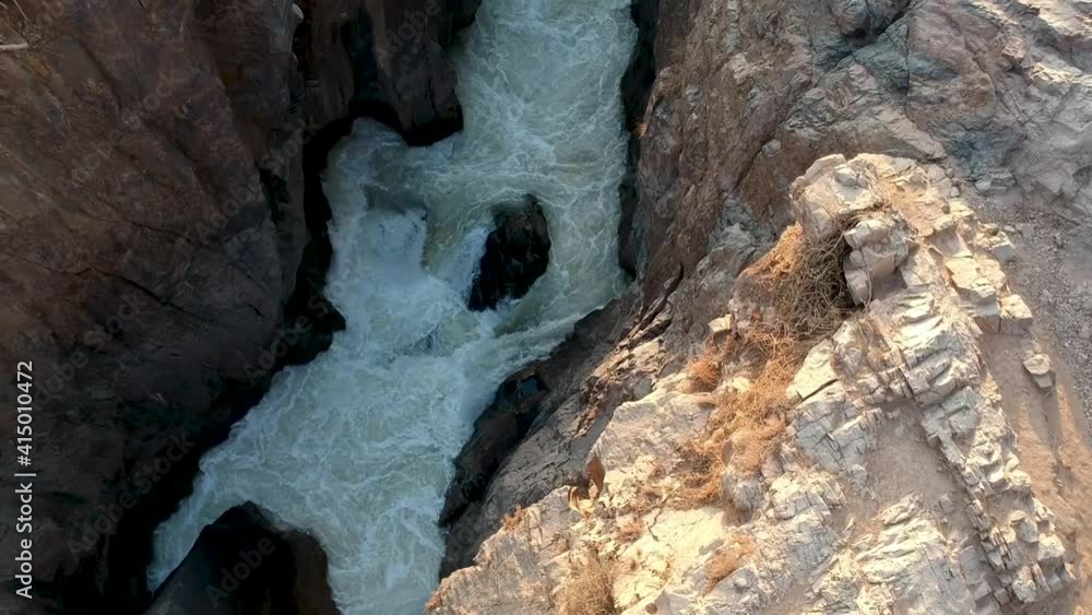 Panning up from deep gorge and water to Epupa falls with big Baobab and the mist from the waterfall with sun setting on the water of the Kunene river Aerial.mp4 Panning up from deep gorge and water to Epupa falls with big Baobab and the mist from the waterfall with sun setting on the water of the Kunene river Aerial.mp4