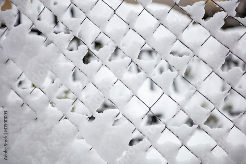 Wire mesh fence covered with snow, winter background
