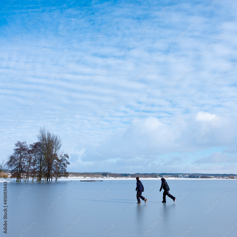 boys play on ice of flood planes near river rhine near Rhenen in Gelderland