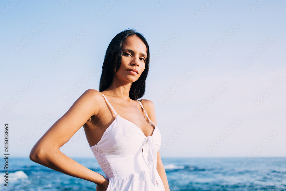 Half length of attractive Latin solo tourist 20 years old posing with sea horizon on background, charming female model looking at camera during leisure time for calm promenade at coastline Half length of attractive Latin solo tourist 20 years old posing with sea horizon on background, charming female model looking at camera during leisure time for calm promenade at coastline
