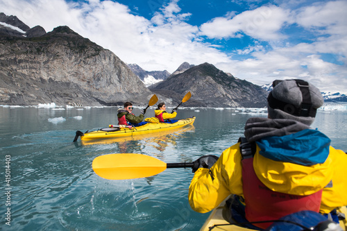 Group of friends enjoy ocean kayaking bear glacier during their vacation trip to in Alaska, USA