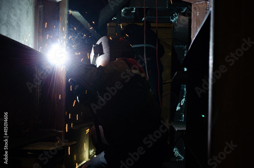Black Steel Metal Welder Worker Welding on a Vertical Position Using Torch for a Sparking Arc