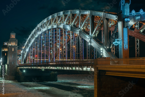 the beautiful metal bridge of Peter the Great across the Neva River in St. Petersburg against the night sky © westermak15