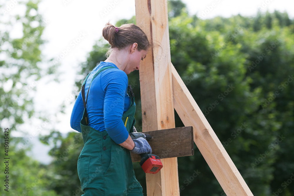 Young woman working with screw driver. Woman is constructing outdoors in summer day. Young woman working with screw driver. Woman is constructing outdoors in summer day.