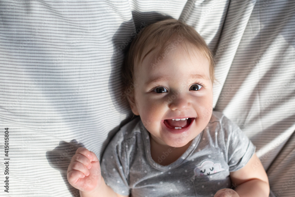 Cute smiling baby girl laying in the bed in morning sun light Cute smiling baby girl laying in the bed in morning sun light