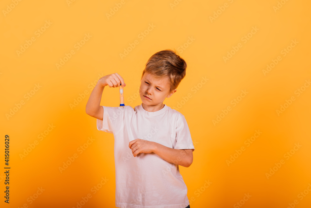 Boy child in a yellow t-shirt on the background in the Studio holding an hourglass Boy child in a yellow t-shirt on the background in the Studio holding an hourglass