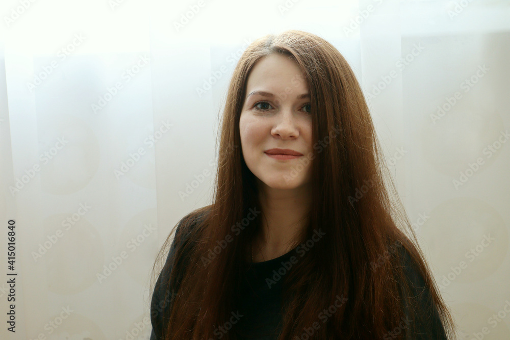 Portrait of a young beautiful cute cheerful girl smiling looking at the camera on a light background Portrait of a young beautiful cute cheerful girl smiling looking at the camera on a light background