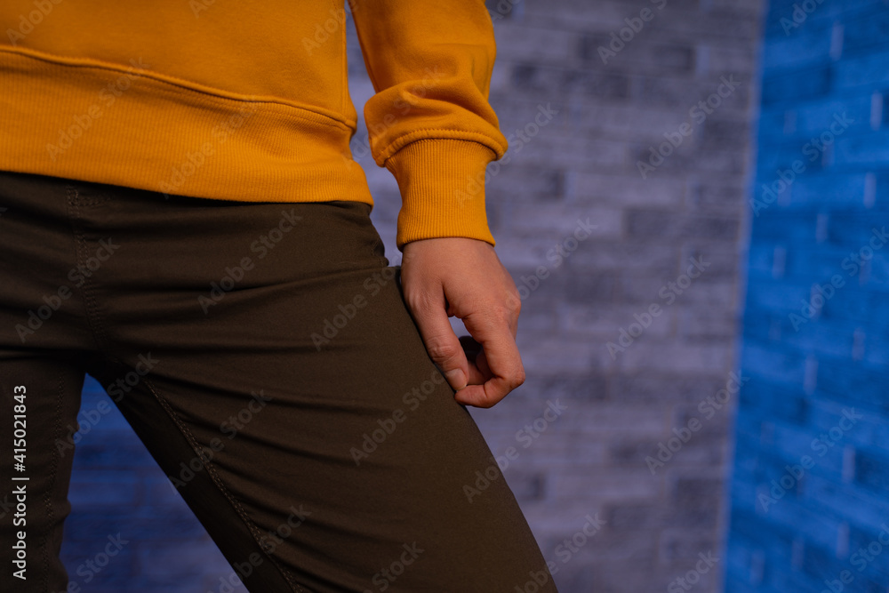 Front view on body part of young female in sweatshirt and trousers. Close up of figure of unrecognizable woman on gray brick background.