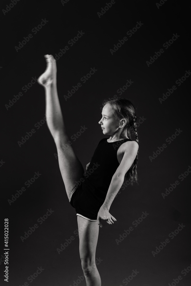 Little girl doing gymnastics with hoop, ball and split isolated on grey background