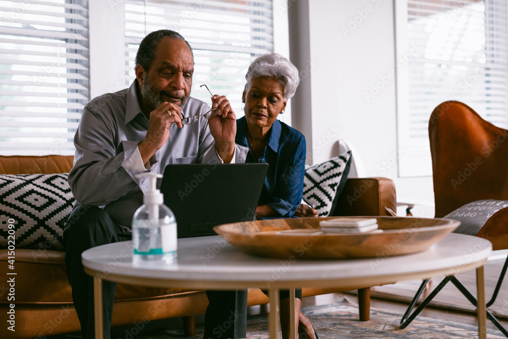 Retired senior couple checking messages on laptop at home Retired senior couple checking messages on laptop at home