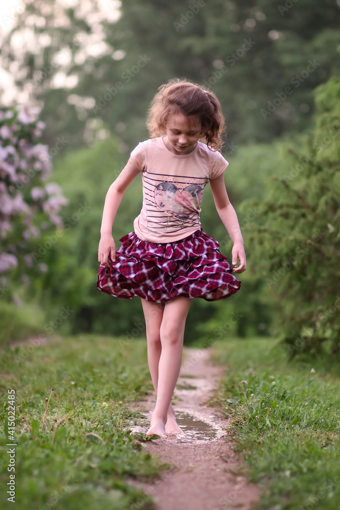 Barefoot girl walks through a puddles of water after the summer rain. Barefoot girl walks through a puddles of water after the summer rain.