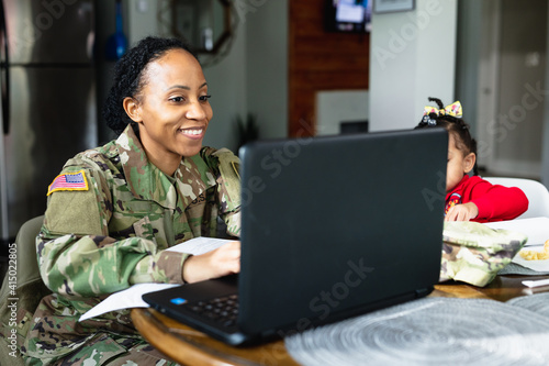 Happy military woman has conversation with family while working from home at laptop