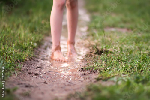 Barefoot girl walks through a puddles of water after the summer rain.