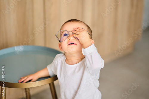 Portrait of cute baby girl trying on adult eyeglasses photo