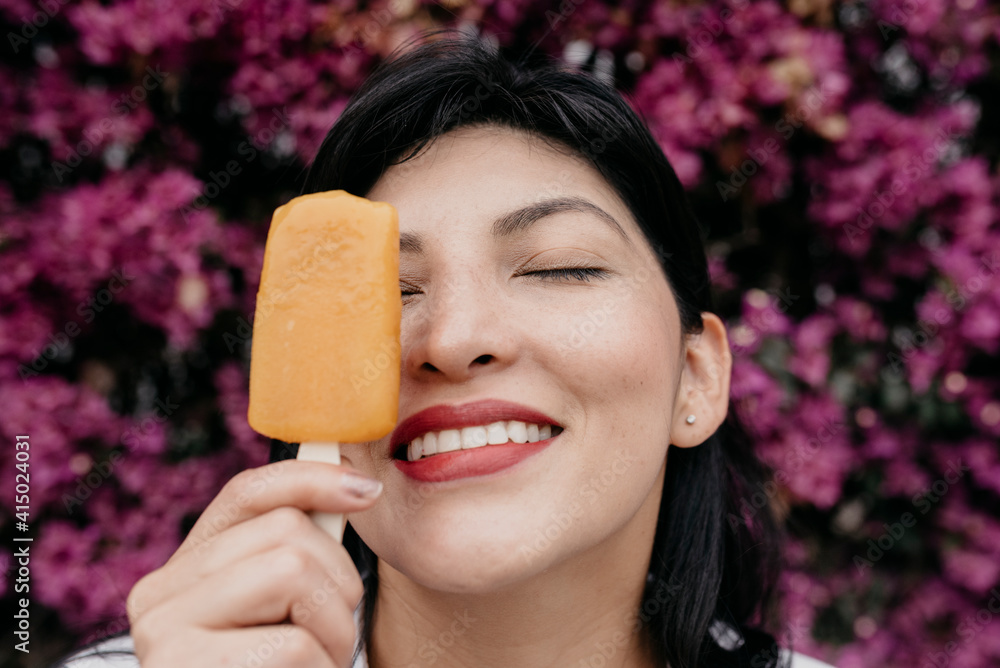 Smiling woman with eyes closed holding ice cream by face at park Smiling woman with eyes closed holding ice cream by face at park