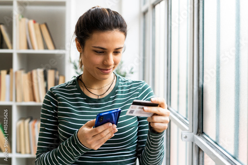 Female entrepreneur paying through credit card while online shopping on mobile phone in office photo