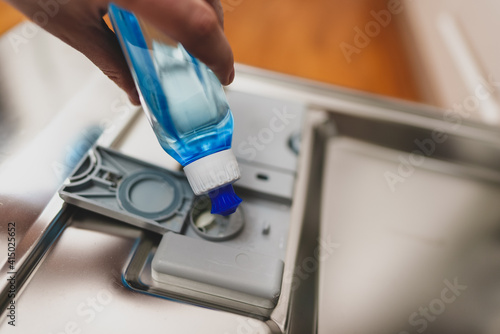 Quadro em tela Man pours rinse aid into the dishwasher compartment.