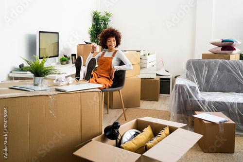 Afro woman looking away while holding coffee cup in living room at new home photo