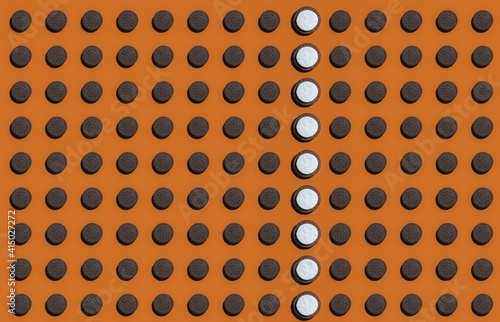 Pattern of rows of brown cookies with single column having white top photo