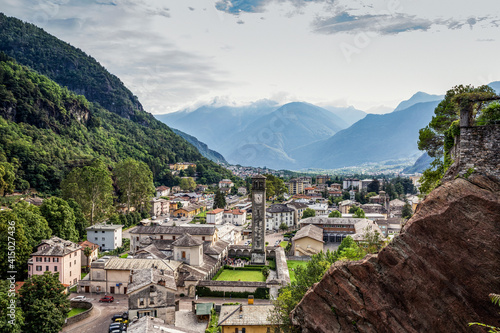 Parrocchia Di San Lorenzo in town by mountain against sky seen from Parco Archeologico Botanico del Paradiso, Valchiavenna, Chiavenna, Province of Sondrio, Lombardy, Italy photo