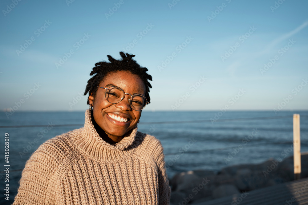 Happy woman smiling while sitting against sea Happy woman smiling while sitting against sea