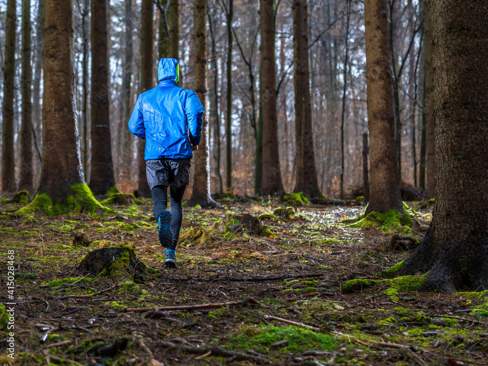 Young man jogging amidst trees in forest during winter Young man jogging amidst trees in forest during winter