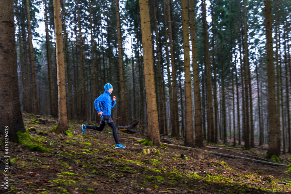 Active young man running on trail in forest Active young man running on trail in forest