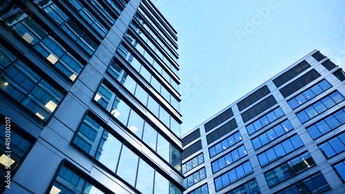 Bottom view of modern skyscrapers in business district against blue sky. Looking up at business buildings in downtown.