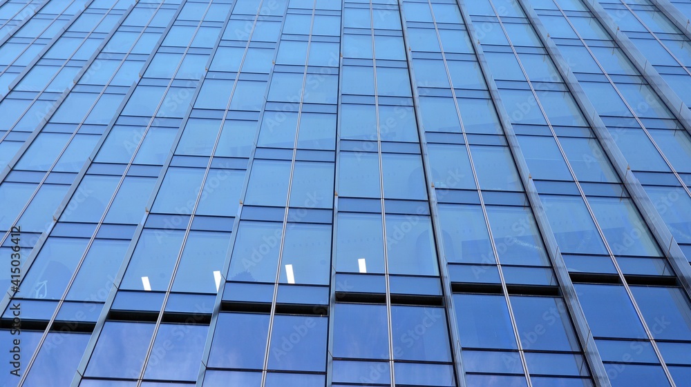 Facade texture of a glass mirrored office building. A beautiful background of an glass office building, reflecting clouds in the windows. Facade texture of a glass mirrored office building. A beautiful background of an glass office building, reflecting clouds in the windows.