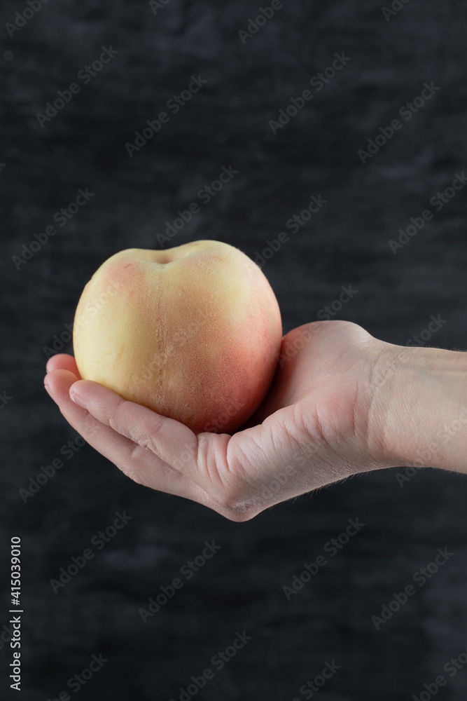 Farmer holding a yellowish redish apple between fingers