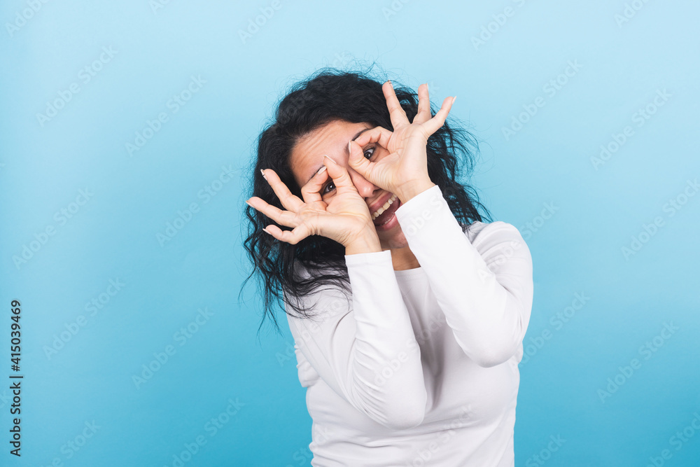 Young brunette woman makes the eyeglasses gesture with her hands Young brunette woman makes the eyeglasses gesture with her hands