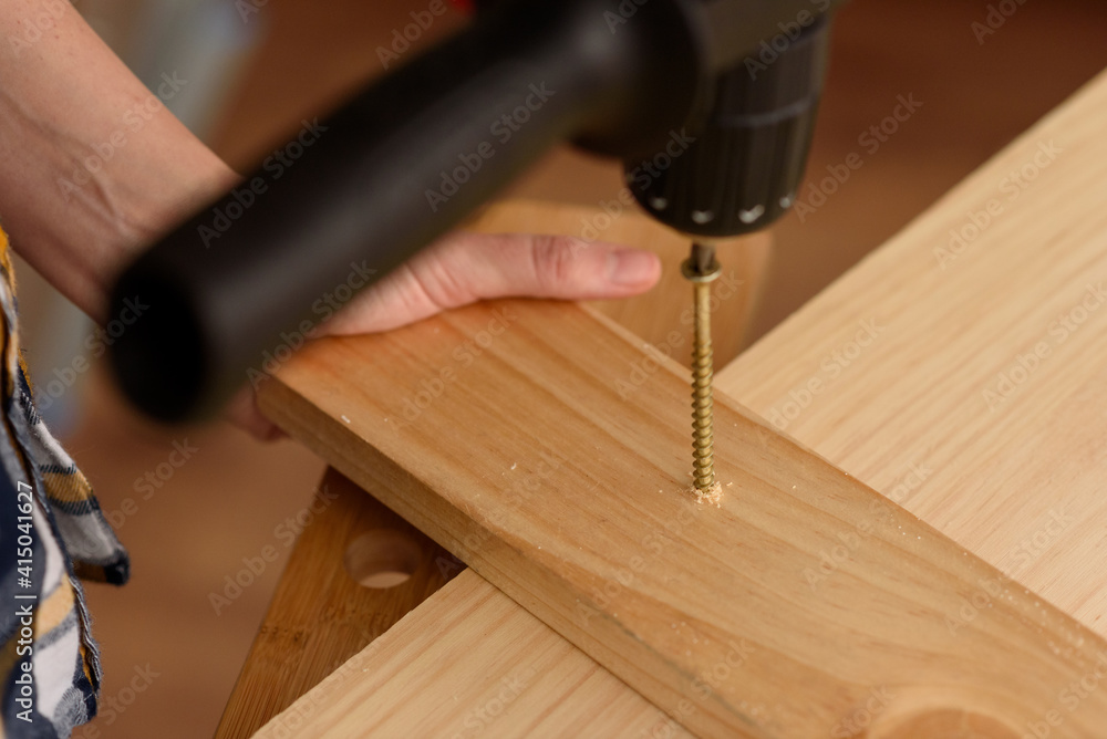Close up of a drill drilling a screw in a piece of wood.