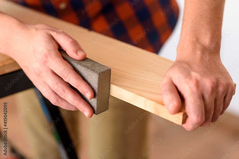 Close up shot of a man at home sanding wood on a workbench. Close up shot of a man at home sanding wood on a workbench.