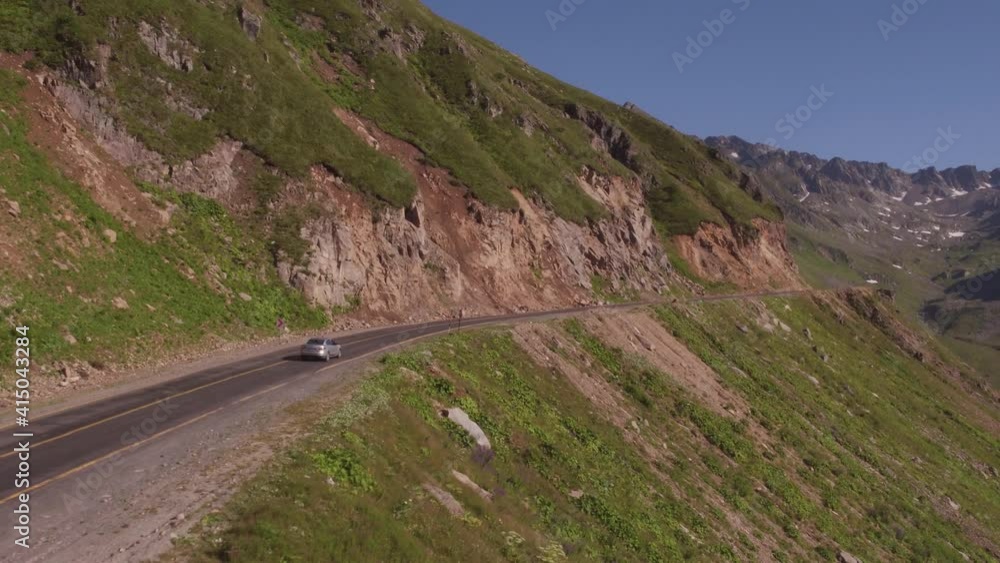 One silver sedan car driving on dangerous serpentine asphalt road. Turkish winding freeway through arid rocky mountains at summer sunny day. Aerial drone view. One silver sedan car driving on dangerous serpentine asphalt road. Turkish winding freeway through arid rocky mountains at summer sunny day. Aerial drone view.