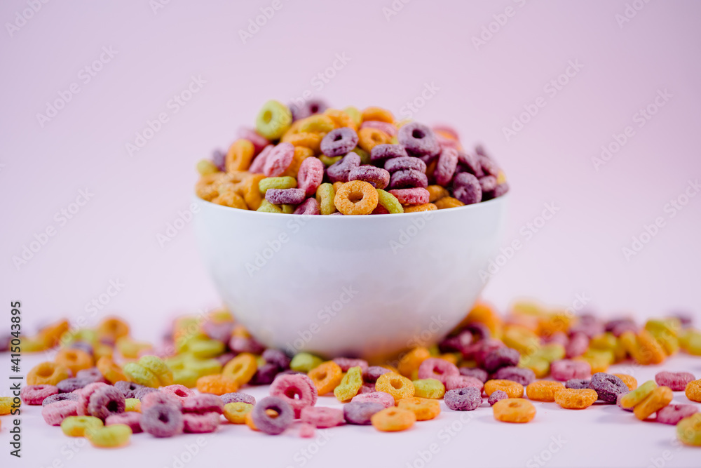 From above pile of colorful cereal rings in bowl prepared for breakfast placed on violet table in studio From above pile of colorful cereal rings in bowl prepared for breakfast placed on violet table in studio