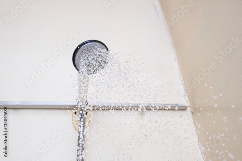 Water flowing from an old shower head with ceramic handle with limescale needed to be replaced or decalcified photo