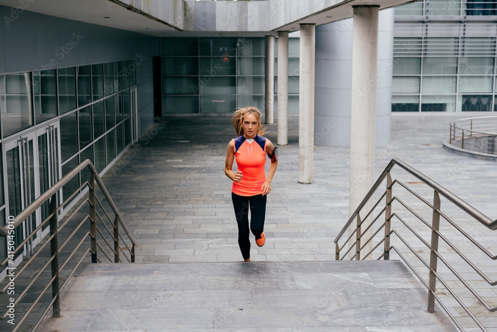 Attractive blonde young woman running up stairs on the street looking at camera Attractive blonde young woman running up stairs on the street looking at camera