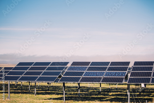 Modern solar panels installed in field against cloudy sky in photovoltaic power station photo