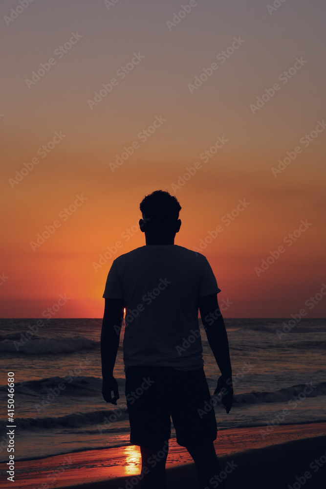 silhouette of a man standing on the beach at sunset