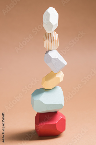 Wooden blocks in shapes of gems of various colors stacked on beige background in studio