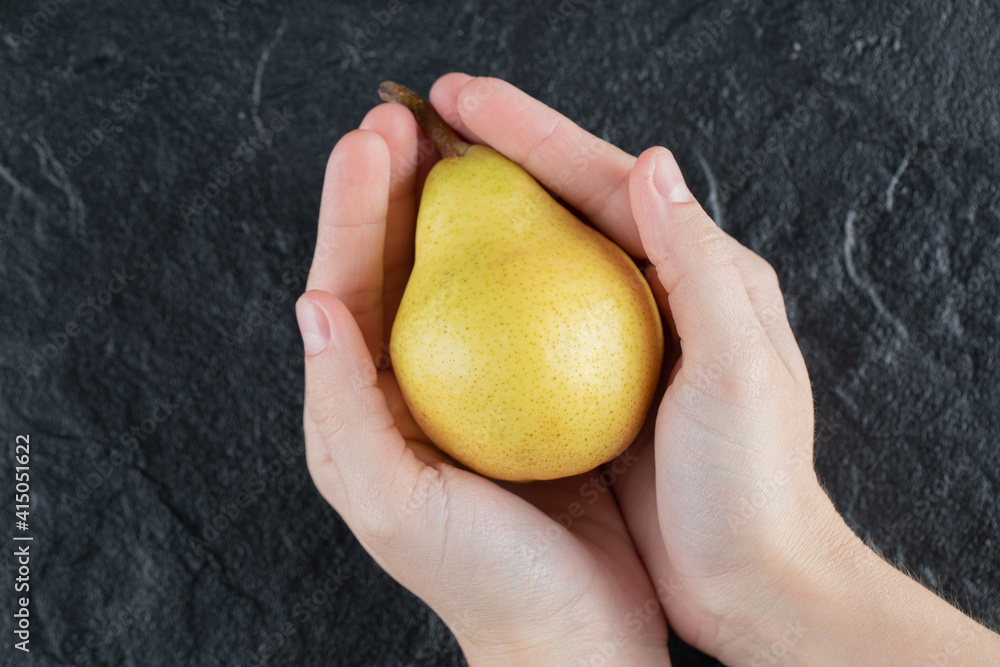 A person holding a yellow pear in both palms A person holding a yellow pear in both palms