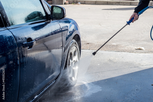 Lavado de coches. Detalle de un hombre limpiando su coche con una manguera de agua a alta presión. © AliciaFdez