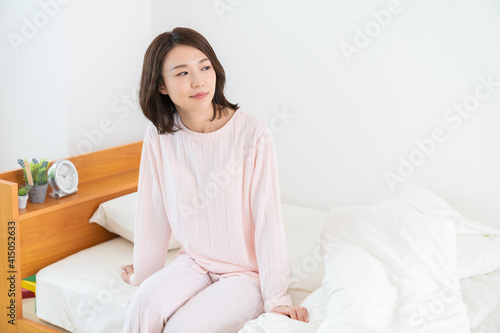 パジャマを着た女性 ベッド 笑顔
