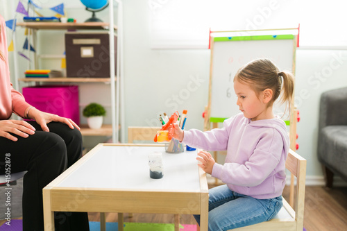 Adorable child using tweezers to hold things and learn motor skills