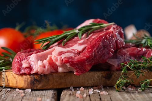 Fresh piece of beef steak with rosemary on the background of the ingredients.Recipe book, dishes with meat .Advertising butcher shops and meat markets banner