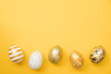 Easter golden decorated eggs on yellow background. Minimal easter concept. Happy Easter card with copy space for text. Top view, flatlay