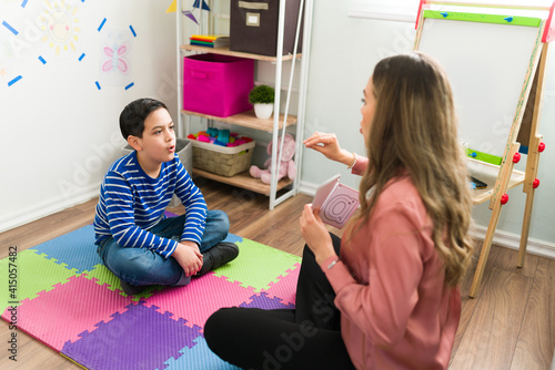 Female psychologist working with a little boy to treat his speech problem