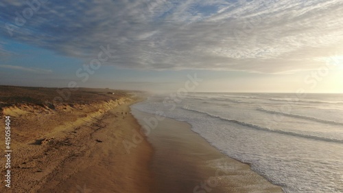 Vue aérienne artistique de la plage avec vagues et dune au coucher du soleil