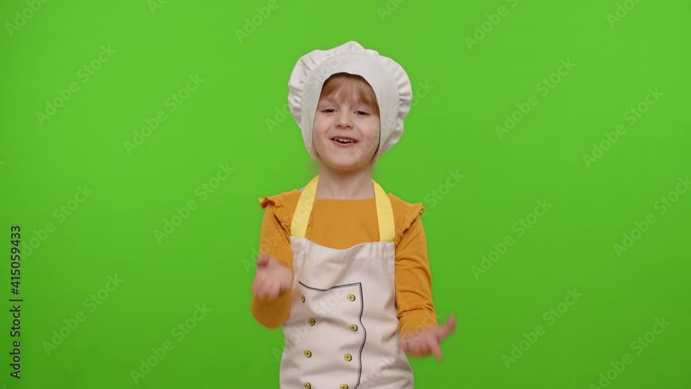 Funny Caucasian child girl dressed cook chef baker in apron and hat waving hands, asking to follow or join, welcome, hello, hi gesture isolated on chroma key background. Cooking advertising store Funny Caucasian child girl dressed cook chef baker in apron and hat waving hands, asking to follow or join, welcome, hello, hi gesture isolated on chroma key background. Cooking advertising store