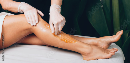 Foto Leg waxing procedure at the spa salon with a caucasian woman lying on bed